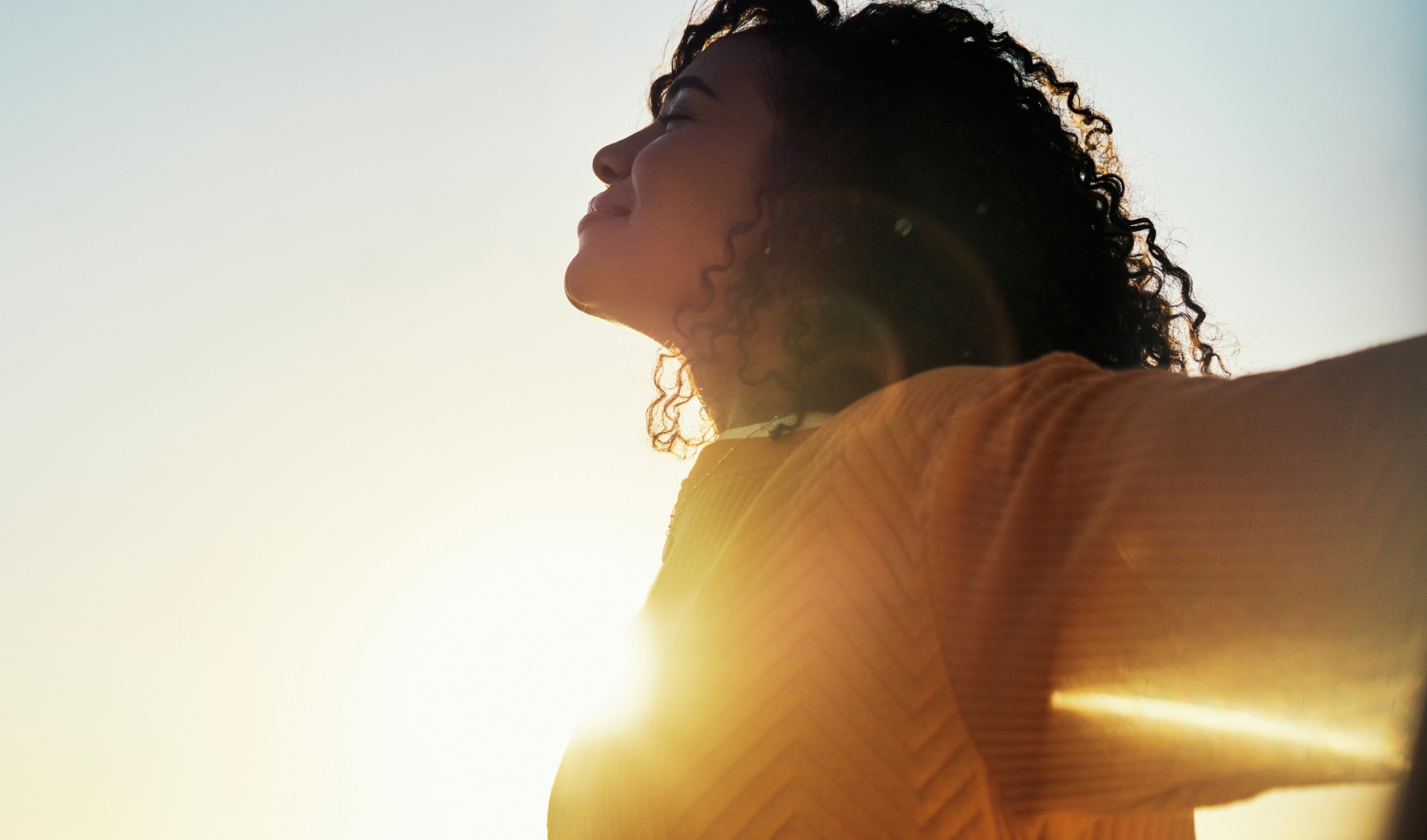 Woman soaking up the sun with arms extended to the horizon